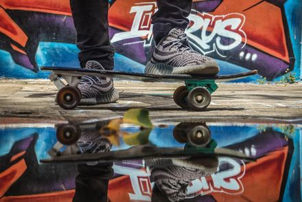 Foto Skateboardfahrer vor einer Mauer mit Grafitti spiegelt sich in einer Pfütze, Urheber: Jose Reyes, Pixabay